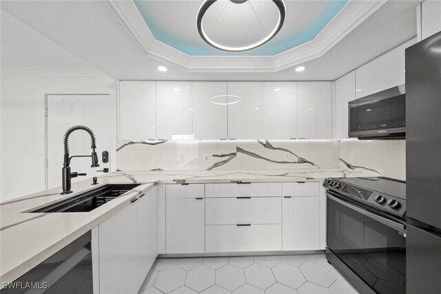 kitchen featuring a raised ceiling, white cabinetry, sink, and appliances with stainless steel finishes