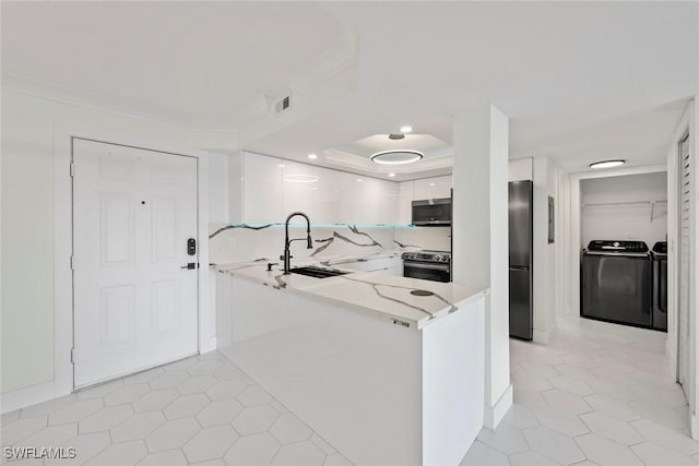 kitchen featuring washing machine and clothes dryer, white cabinetry, sink, stainless steel appliances, and kitchen peninsula