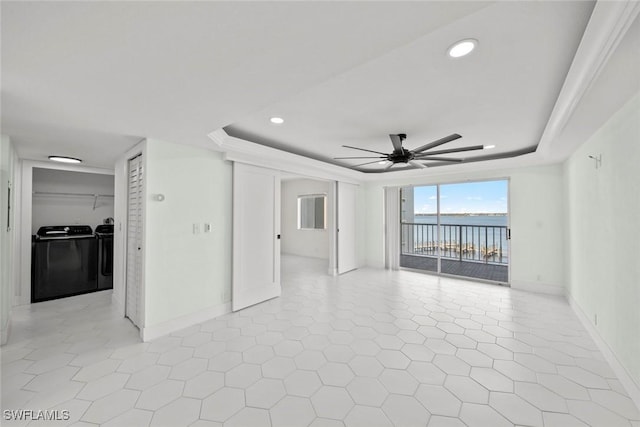 empty room featuring a raised ceiling, ceiling fan, and washing machine and dryer