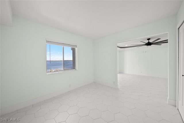 tiled empty room with ceiling fan and a water view