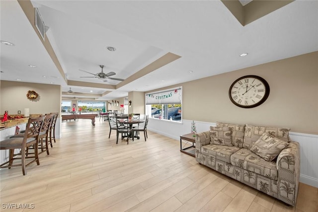 living room with a tray ceiling, ceiling fan, billiards, and light wood-type flooring