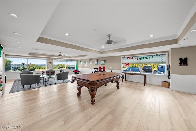 rec room featuring ceiling fan, a raised ceiling, and light wood-type flooring