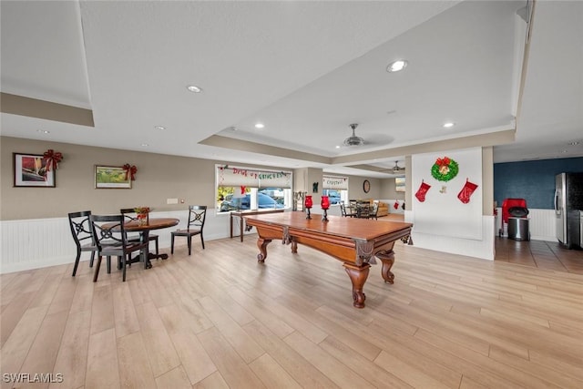 recreation room with a tray ceiling, ceiling fan, pool table, and light wood-type flooring