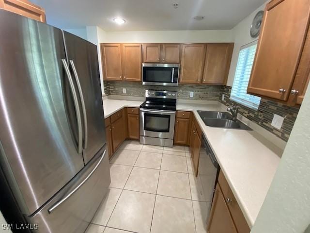 kitchen with backsplash, appliances with stainless steel finishes, sink, and light tile patterned floors