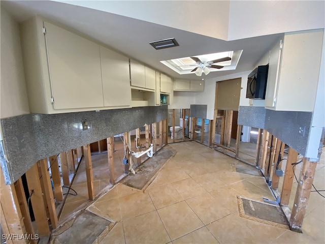 kitchen with ceiling fan, light tile patterned flooring, and a raised ceiling