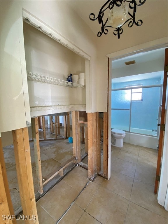 bathroom with tile patterned flooring, toilet, and enclosed tub / shower combo