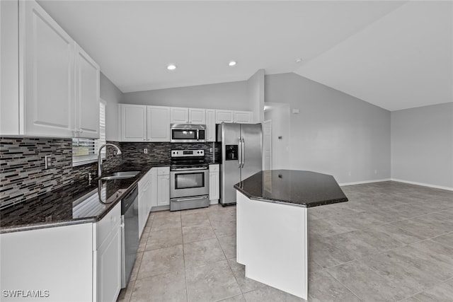 kitchen with sink, a kitchen island, vaulted ceiling, white cabinets, and appliances with stainless steel finishes