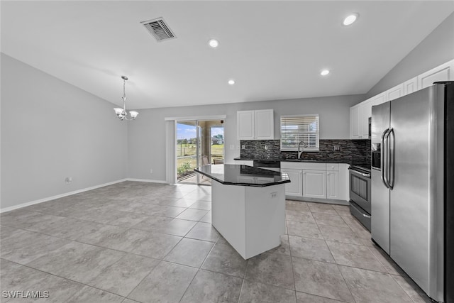 kitchen featuring appliances with stainless steel finishes, white cabinetry, vaulted ceiling, and a kitchen island