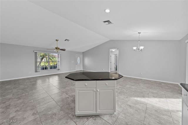 kitchen with ceiling fan with notable chandelier, vaulted ceiling, a kitchen island, white cabinetry, and hanging light fixtures