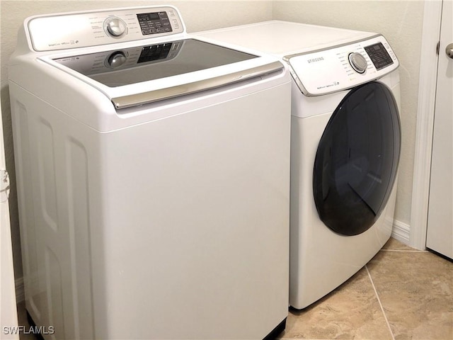 clothes washing area featuring light tile patterned floors and washer and clothes dryer