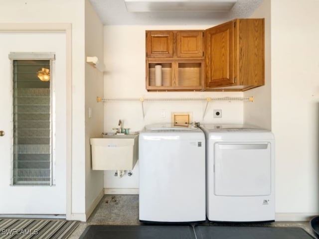 washroom with cabinets, washing machine and dryer, and sink