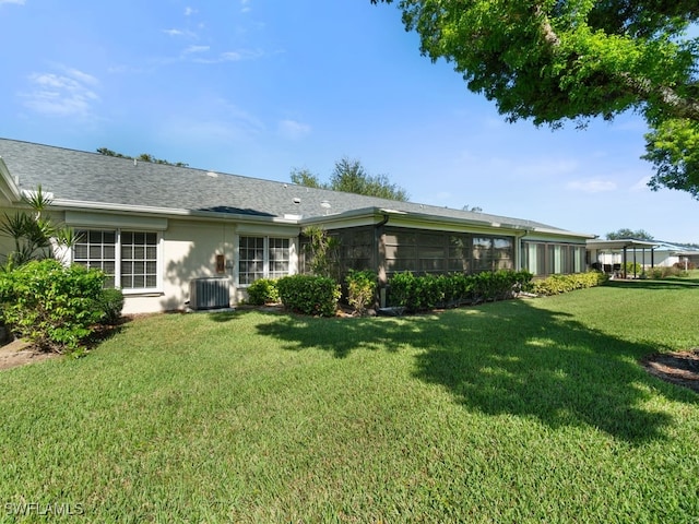 back of property featuring a sunroom, a yard, and central AC