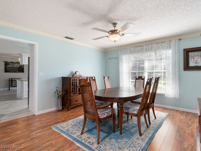 dining space with wood-type flooring, a textured ceiling, ceiling fan, and ornamental molding