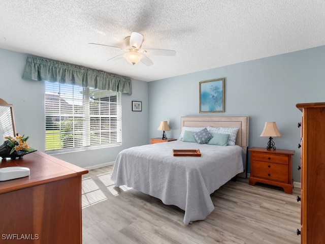 bedroom with ceiling fan, a textured ceiling, and light hardwood / wood-style flooring