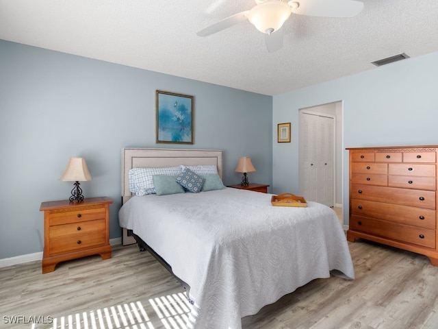 bedroom featuring a textured ceiling, light wood-type flooring, a closet, and ceiling fan