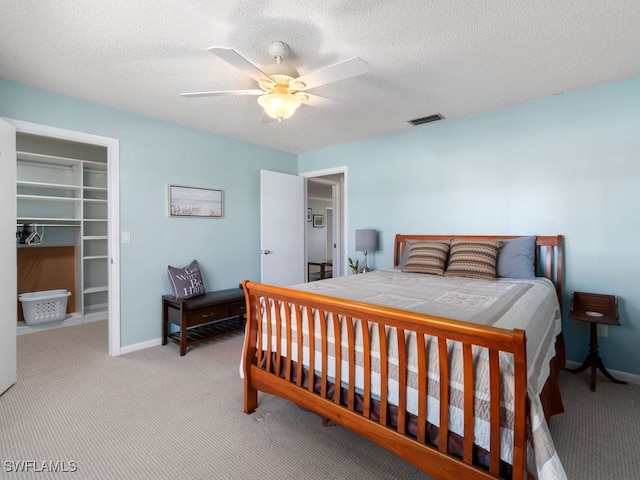 bedroom featuring ceiling fan, light colored carpet, a textured ceiling, and a closet