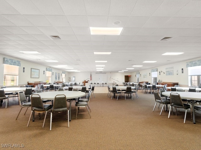 carpeted dining room with a drop ceiling