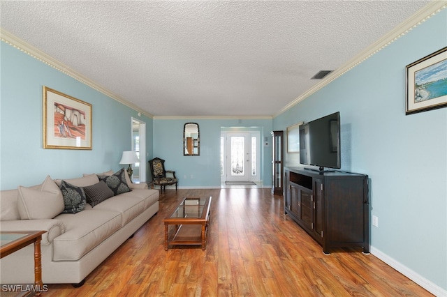 living room with light hardwood / wood-style floors, ornamental molding, a textured ceiling, and french doors