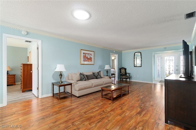 living room featuring crown molding, a textured ceiling, and light wood-type flooring