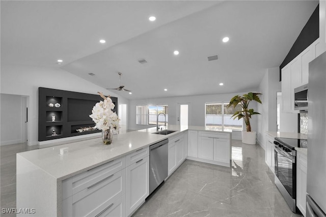 kitchen featuring lofted ceiling, sink, appliances with stainless steel finishes, light stone counters, and white cabinets