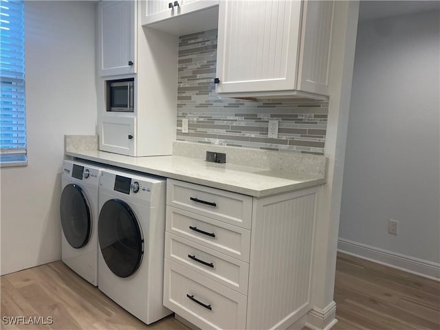 laundry room with cabinets, light hardwood / wood-style flooring, and washer and clothes dryer