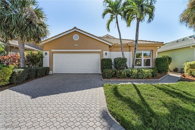 ranch-style house featuring stucco siding, a tile roof, decorative driveway, a front yard, and a garage