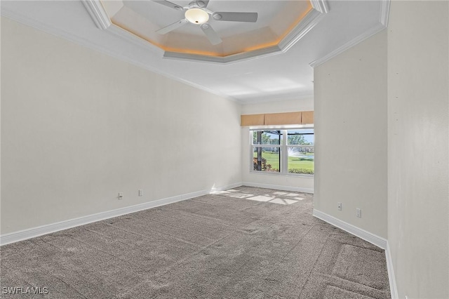 spare room featuring crown molding, ceiling fan, baseboards, a tray ceiling, and carpet flooring