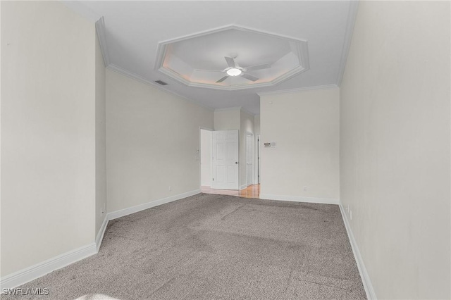 carpeted empty room featuring visible vents, crown molding, ceiling fan, baseboards, and a raised ceiling