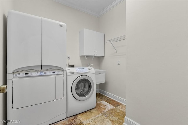 washroom featuring stone finish flooring, baseboards, ornamental molding, cabinet space, and independent washer and dryer