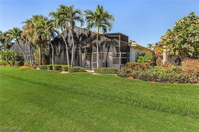 back of house featuring a lanai and a yard