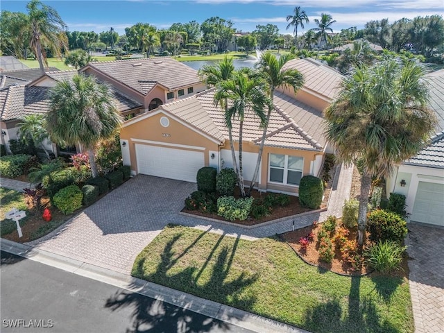 mediterranean / spanish home featuring stucco siding, decorative driveway, an attached garage, and a tile roof