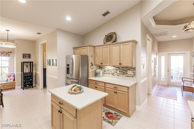 kitchen featuring tasteful backsplash, light brown cabinets, stainless steel fridge, a kitchen island, and pendant lighting