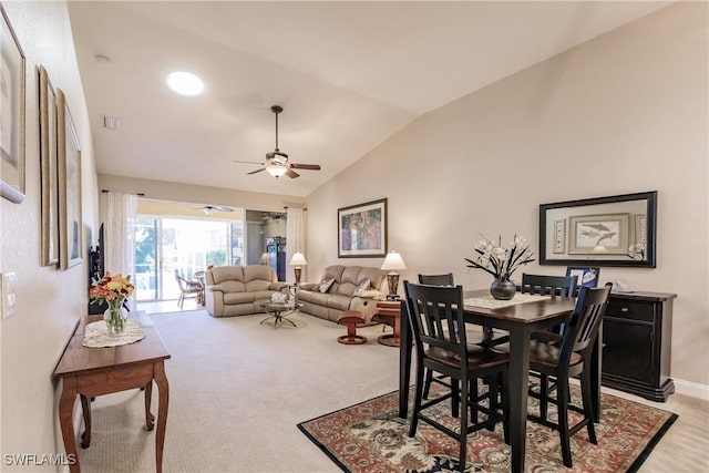 dining room with ceiling fan, light colored carpet, and vaulted ceiling