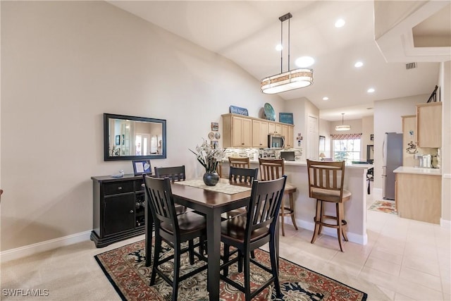 dining area with light tile patterned floors and vaulted ceiling