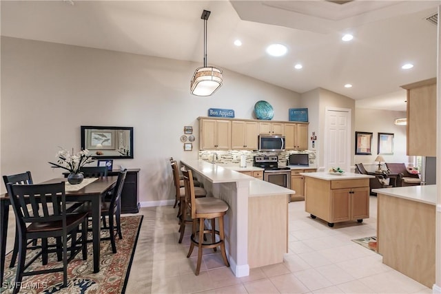 kitchen with hanging light fixtures, a center island, kitchen peninsula, stainless steel appliances, and light brown cabinets