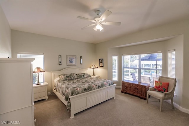 carpeted bedroom featuring multiple windows and ceiling fan