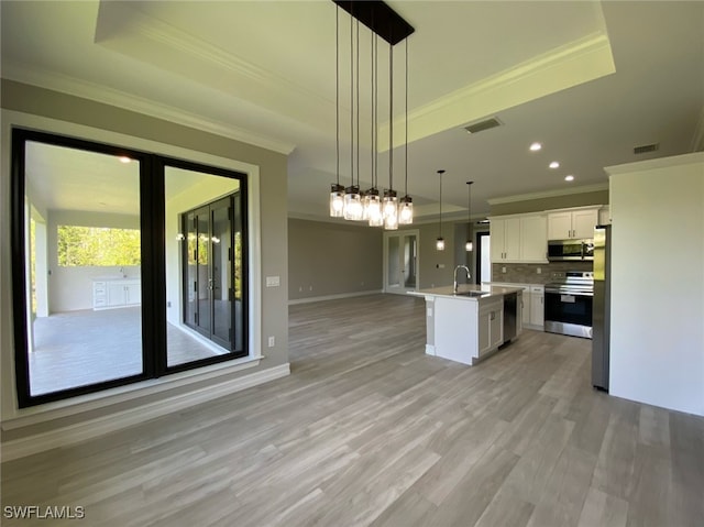 kitchen featuring stainless steel appliances, sink, decorative light fixtures, a center island with sink, and white cabinets