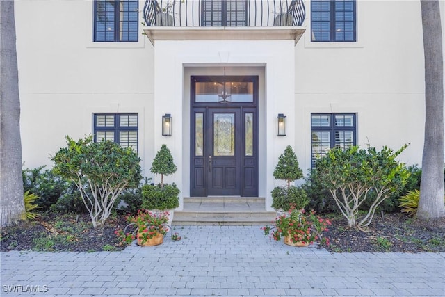 55 E Burning Tree Dr, Naples, FL 34105 - doorway to property with stucco siding and a balcony