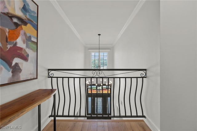 hallway with light hardwood / wood-style floors, crown molding, and a chandelier