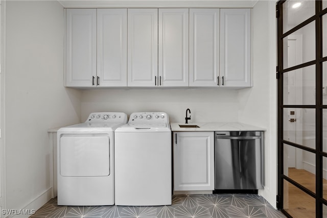 clothes washing area featuring washer and dryer, cabinets, and sink