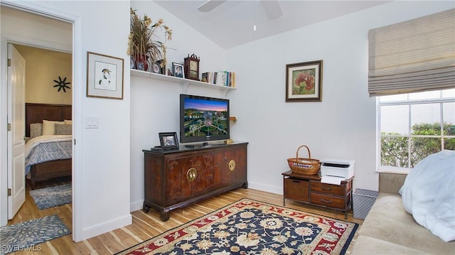 living area featuring a ceiling fan, vaulted ceiling, baseboards, and wood finished floors