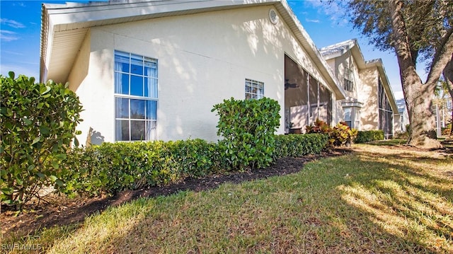 view of side of property with a yard and stucco siding