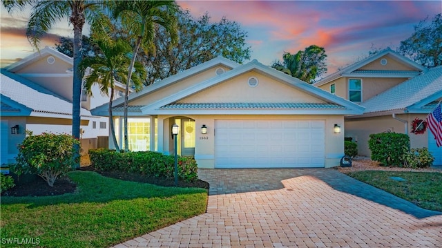 view of front facade with an attached garage, a front lawn, decorative driveway, and stucco siding