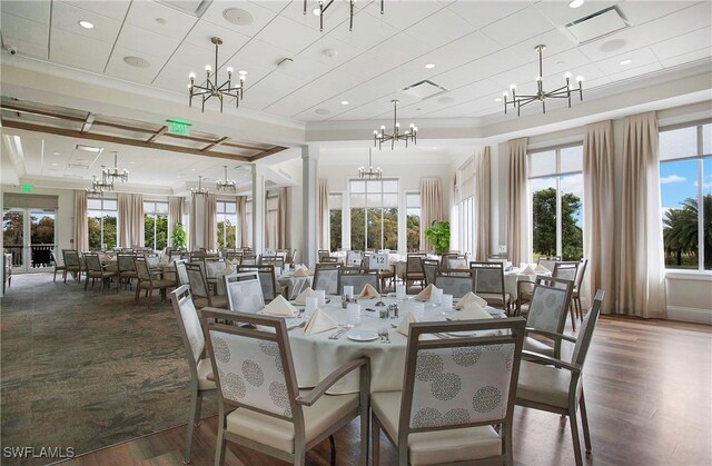 dining space with visible vents, dark wood-style floors, an inviting chandelier, decorative columns, and crown molding