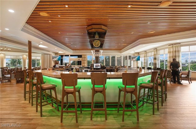 bar featuring a community bar, a tray ceiling, wood ceiling, and light wood-style flooring