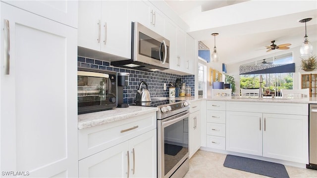 kitchen with stainless steel appliances, ceiling fan, sink, white cabinets, and hanging light fixtures