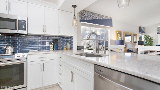 kitchen featuring decorative backsplash, light stone counters, stainless steel appliances, white cabinetry, and a sink