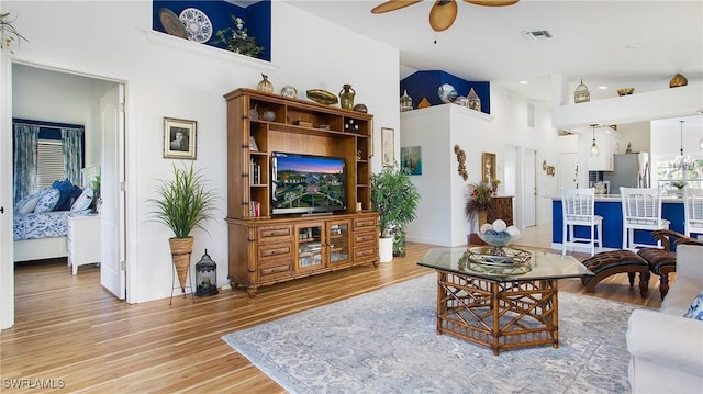 living room featuring ceiling fan, hardwood / wood-style floors, and a high ceiling