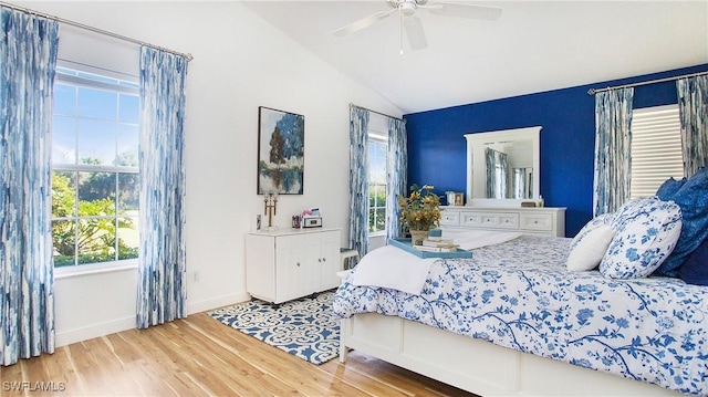 bedroom with multiple windows, ceiling fan, lofted ceiling, and hardwood / wood-style flooring