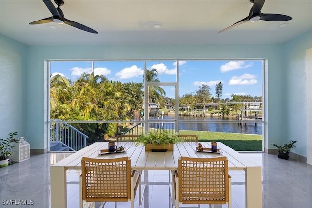 sunroom / solarium featuring ceiling fan and a water view